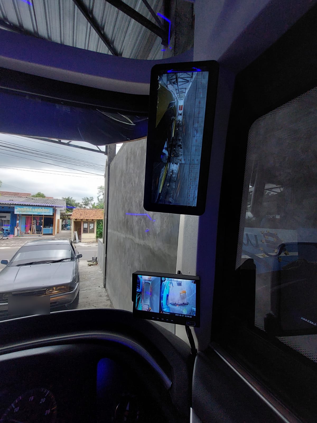 Layar kamera belakang dan kamera sekeliling bus yang terpasang di samping pengemudi untuk membantu manuver